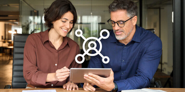 An image showing two colleagues working together while looking at a tablet screen.
