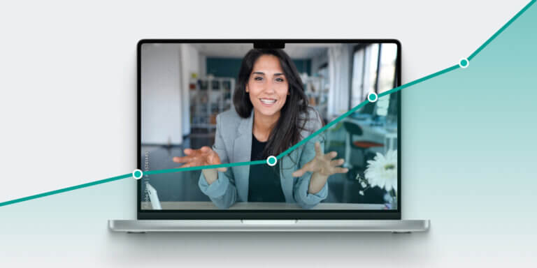 An image showing a woman with long, dark hair smiling and communicating something through a laptop screen.