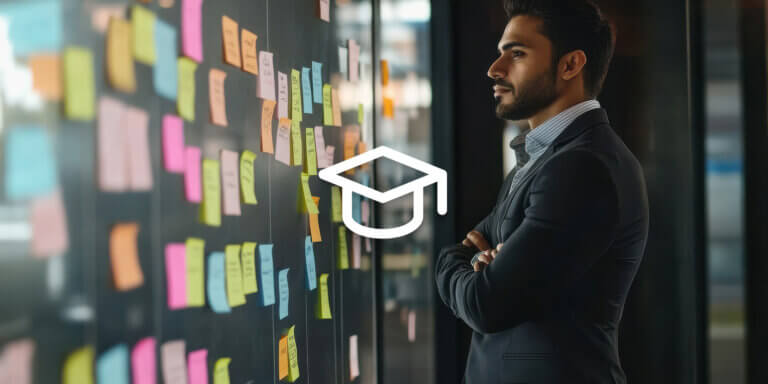 An image showing a man in a suit standing with hands crossed, looking at a wall with colourful post-its.