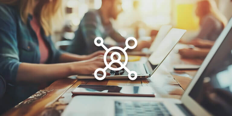 A visual showing a centered person icon with a blurry background featuring people working on their laptops while sitting at a desk.