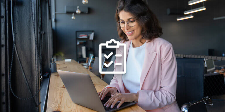 Alt-text: A woman wearing glasses and pink shirt using a laptop.