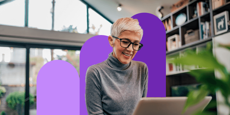 A woman with short blond hair and black glasses is using a laptop screen.